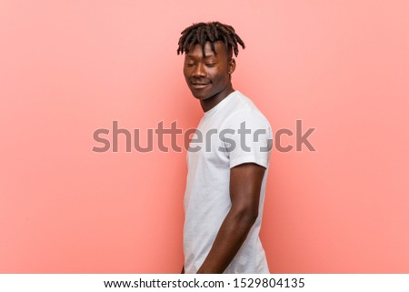 Young african black man looks aside smiling, cheerful and pleasant.