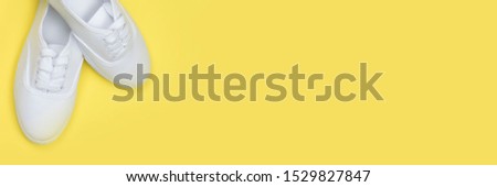 
White women's sports shoes on a bright yellow background, banner,minimal style.