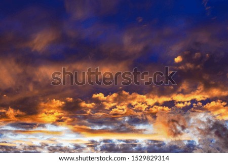 Dramatic sky at sunset or sunrise with red and orange clouds. Variegated colored clouds at the evening sunset of the summer sky.