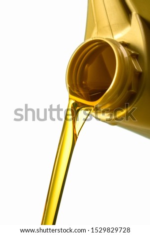 Filling engine oil from a golden canister. Canister with a splash of engine oil isolated on a white background close-up.