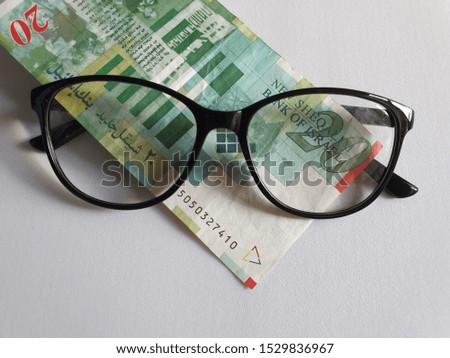 investment and promotion for a better vision, Israeli banknote of twenty shekels and black plastic frame glasses