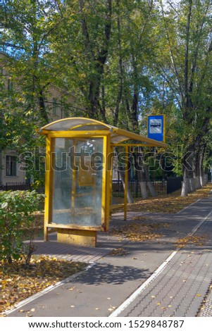 yellow iron bus stop with a traffic sign and a place for an advertising poster on a small city street