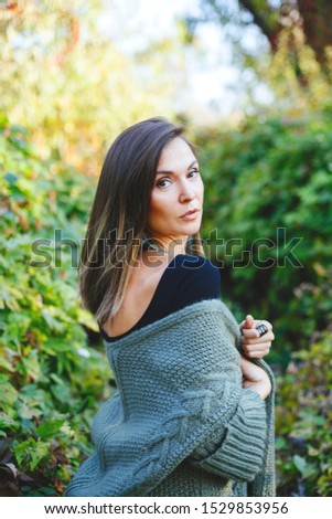 Charming brunette woman in autumn clothes posing in the park