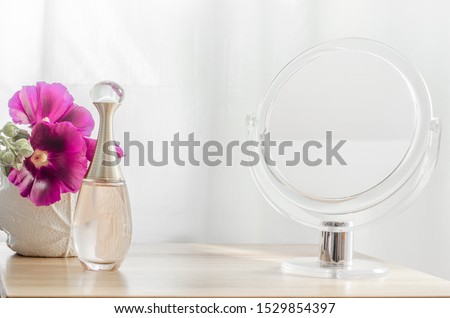 Perfume bottle, flowers and mirror decoration on dressing table.