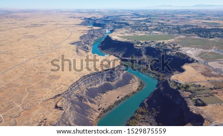 This is a drone picture of the snake river over Twin Falls Idaho with the waterfalls visible in the background. 