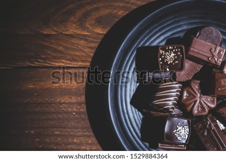 Pralines on plate  on wooden base, 
deep shadows, close up. sweet and chocolate concept.