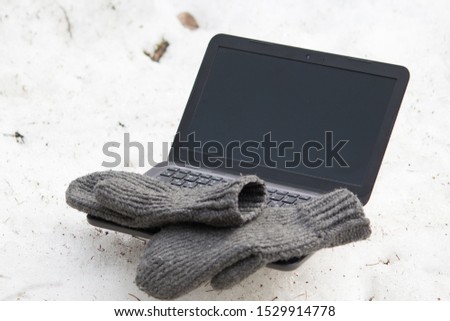 laptop for remote work in the winter in nature in poor conditions with hands in mittens. still life: mittens are lying on a laptop on the floor in the forest for advertising remote work