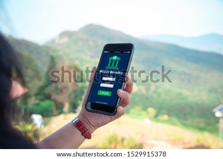 Mobile banking concept.Female hands using mobile phone on blurred green mountain as background