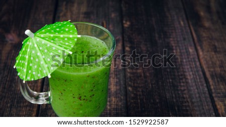 Green fresh smoothie with kiwi, green fruit on dark wooden background. The concept of healthy eating, drinking mixed fruit. Delicious fruit breakfast, fresh juices.