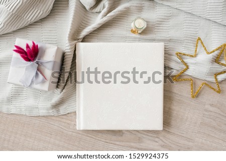 Beautiful wedding photo book in leather with embossed lace surrounded by gift box and stars on plaid and Board background