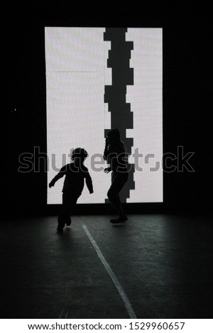 The silhouette of a young child running in front of a white light art instillation at Nuit Blanche, which translates to "white night", and is an annual all-night arts festival.  Image has copy space.
