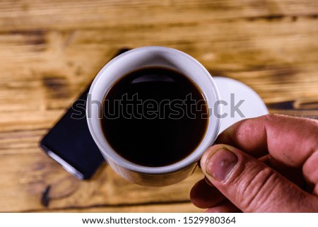 Modern smartphone with blank screen on a wooden background and hand with cup of coffee