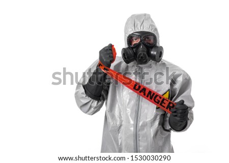 A man poses in a gray protective suit winding a red protective tape around his hand. Isolated background. Dangerous sign