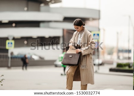 A beautiful businesswoman of Asian appearance pulls out a folder with documents from a leather briefcase