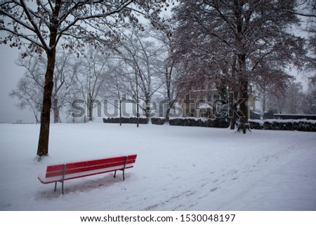 Red bench in the middle of a snowy park in Lucerne, Switzerland
