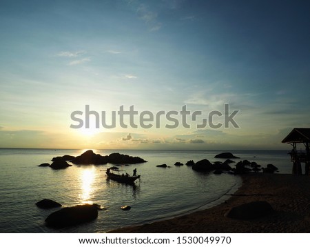 a scenic romantic landscape background picture of sunset on the horizon skyline in the ocean form the coast and the sun light reflecting with the sea water with ship sailing across the ocean .