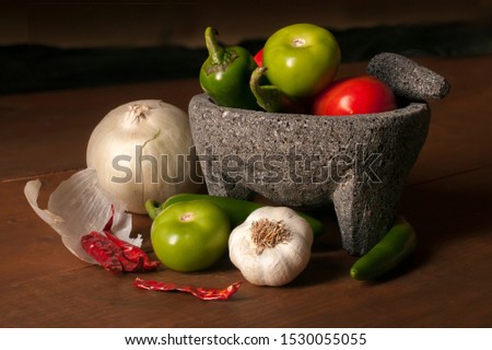 Mexican Molcajete and vegetables to make salsa on a wooden rustic table Royalty-Free Stock Photo #1530055055