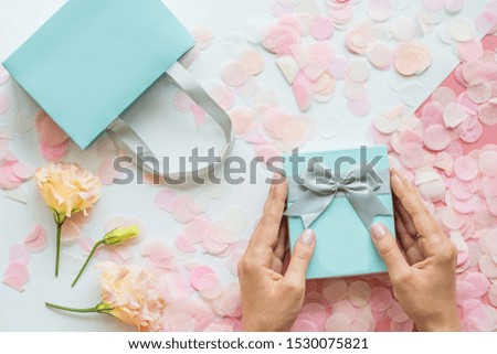 Gift or present box, hands and confetti on pink table top view. Flat lay composition for birthday, mother day, 8 march, xmas, christmas, new year, valentine day or wedding. Holiday concept