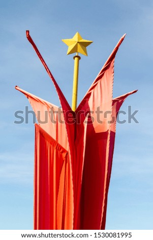 Red flags, five-pointed star, against the sky.
