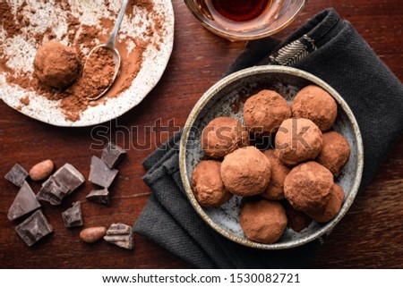 Homemade dark chocolate truffles on plate, brown wooden background. Table top view. Chocolate candy balls