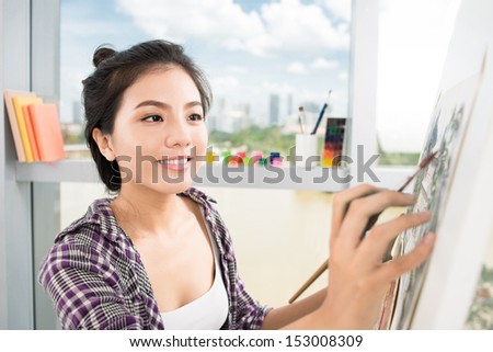 Close-up image of a lovely artist busy with painting on the foreground