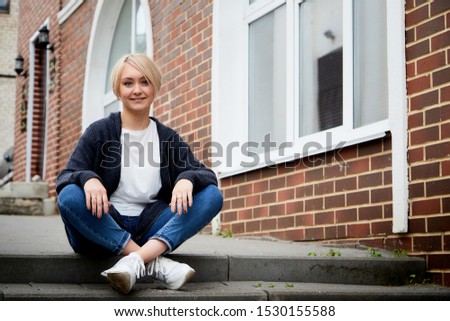 Blonde girl on the steps of pavement in the Central part of the ancient city. Walk in downtown. Portrait of a funny pretty girl on the street of the town