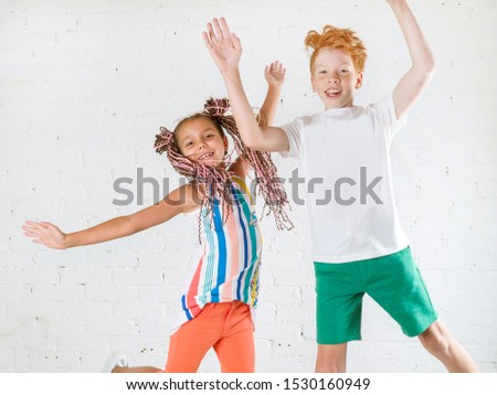 Beautiful happy kids in fashionable clothes jumping on a white background