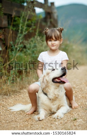 A child with a dog. Little girl plays with a dog in nature. 