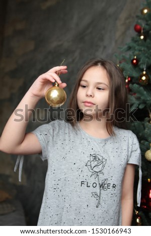 A little girl at Christmas opens gifts. The child decorates the Christmas tree with balls. Happy holiday. Magical new year