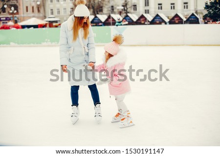 Family in a winter park. Mother with daughter in a ice arena