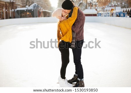 Beautiful couple have fun in a ice arena. Elegant girl in a yellow sweater.