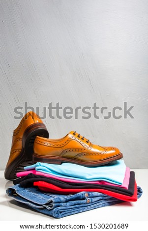 Pair of Male Full Brogued Tan Oxford Shoes Placed on Top of Heap Of Clothing. Vertical Image Composirion