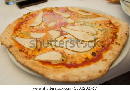 Big Italian pizza with fresh pears, tomato sauce and Gorgonzola blue cheese