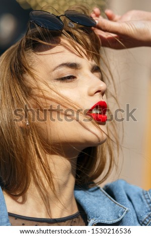 Closeup portrait of magnificent young woman with red lips wears jeans jacket