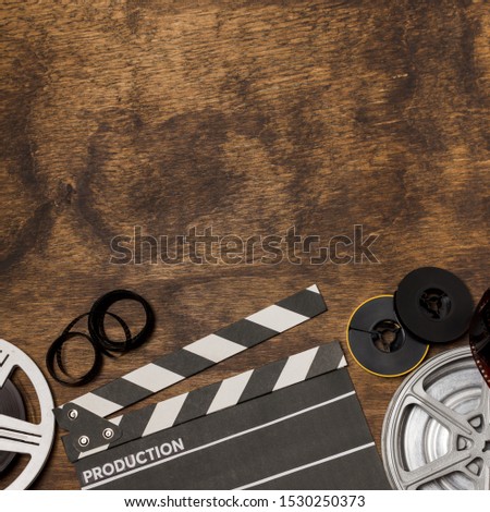 Film stripes; film reel and clapperboard on wooden desk