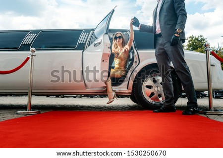 Driver helping VIP woman or star out of limo on red carpet to a reception Royalty-Free Stock Photo #1530250670