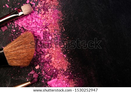 Make-up brushes and crushed cosmetics, shot from above on a black background with a place for text, a beauty design template for a makeup banner