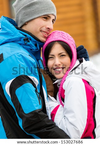 Portrait of embracing couple who wears warm caps and jackets during winter holidays