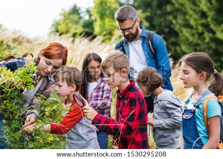 Group of school children with teacher on field trip in nature, learning science. Royalty-Free Stock Photo #1530295208