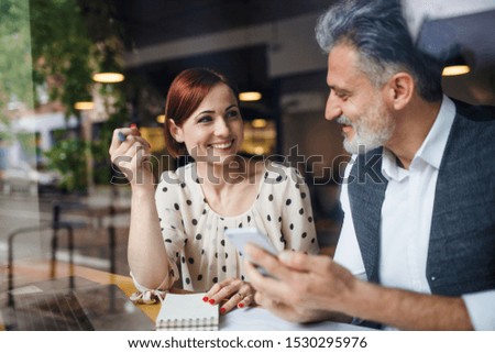 Man and woman having business meeting in a cafe, using smartphone. Royalty-Free Stock Photo #1530295976