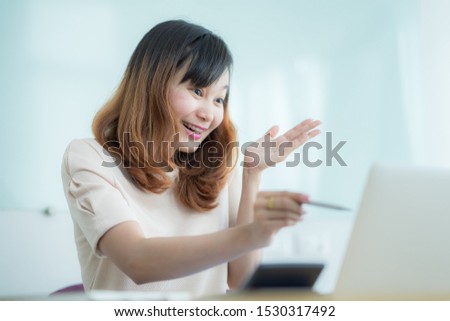 Asian businesswoman laughing with joy at workplace, gladly looking at laptop screen, feeling excited about online win, watching funny video on computer, enjoying positive good news in internet