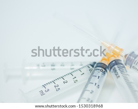 Number 3 syringe, overlapping the amount of 5 pieces on the white surface with the needle no. 25 attached to the tip.