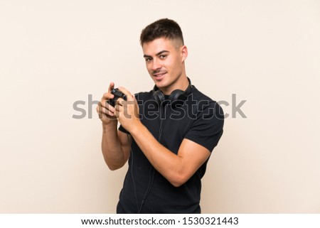 Young handsome man playing with a video game controller over isolated background with happy expression