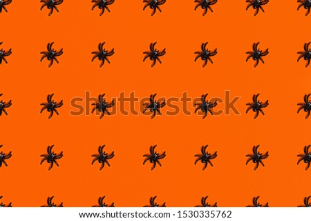 Halloween pattern - orange background with spiders. Flat lay, top view.