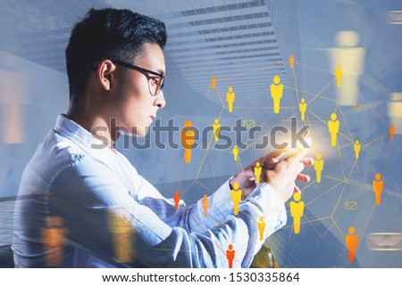 Side view of serious young Asain businessman in glasses working with smartphone with double exposure of HR interface. Concept of job search. Toned image