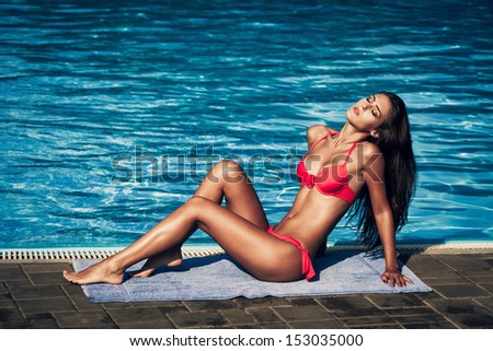 attractive young woman in red bikini by the pool