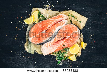 Salmon steaks on black wooden background, red fish, top view, photo filtered in vintage style