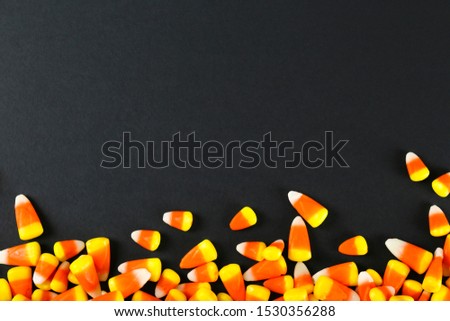 Bunch of candy corn sweets as symbol of Halloween holiday on textured background with a lot of copy space for text. Flat lay composition for all hallows eve. Top view shot.