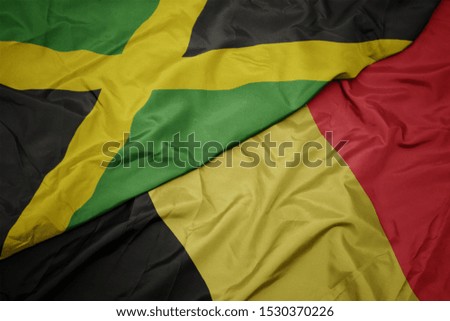waving colorful flag of belgium and national flag of jamaica. macro