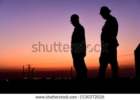 Silhouette of oilfield worker in the oilfield at sunset 